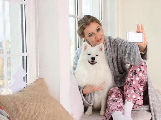 A woman is taking a selfie with her fluffy white dog